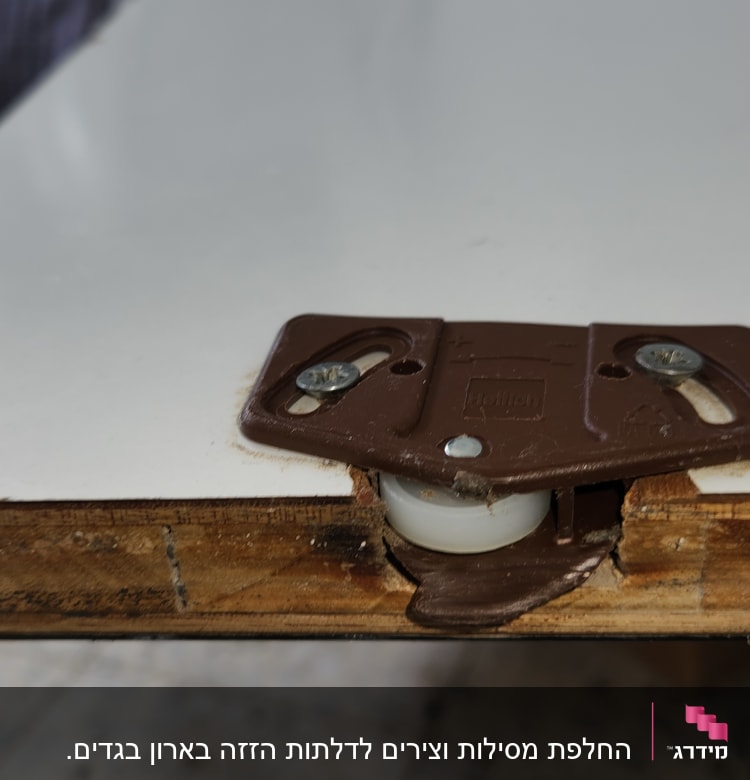 גלגל פלסטיק חום מחובר ללוח עץ עם ברגים